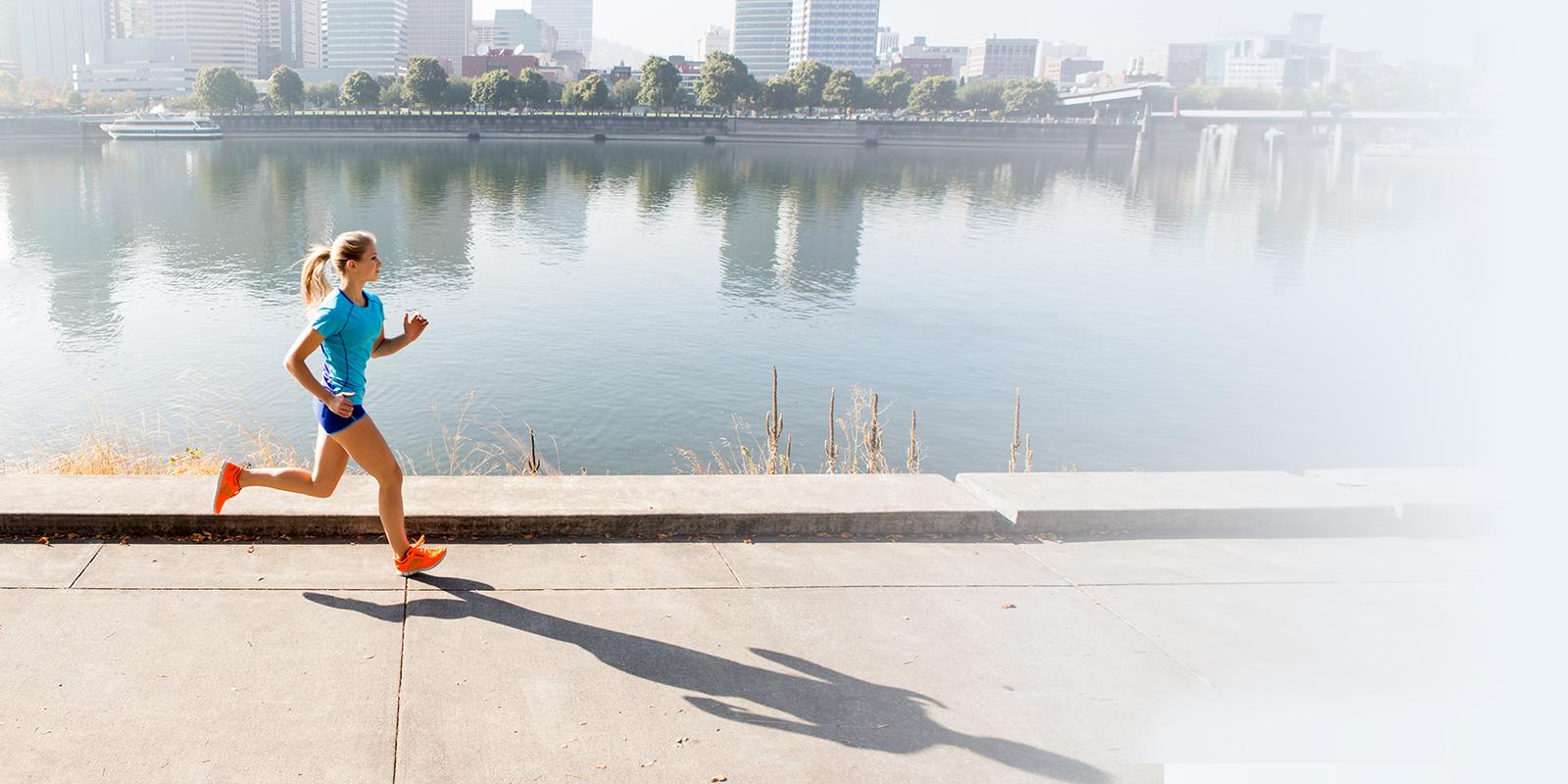 Young female athlete running by a river