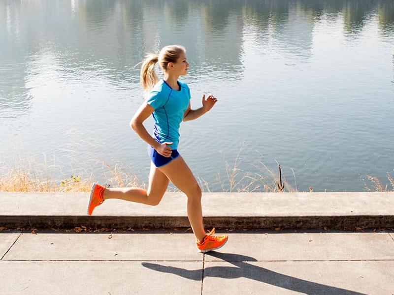 Young female athlete running by a river